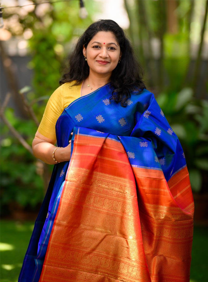 A borderless kolam butta kanchivaram in shot color peacock blue and rust orange.