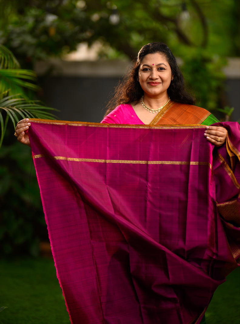 Pure silk, pure zari semi-contrast Ganga Jamuna Kanchivaram featuring a beautiful parrot green kattam on a leaf green body, with delicate floral buttas woven within the checks.