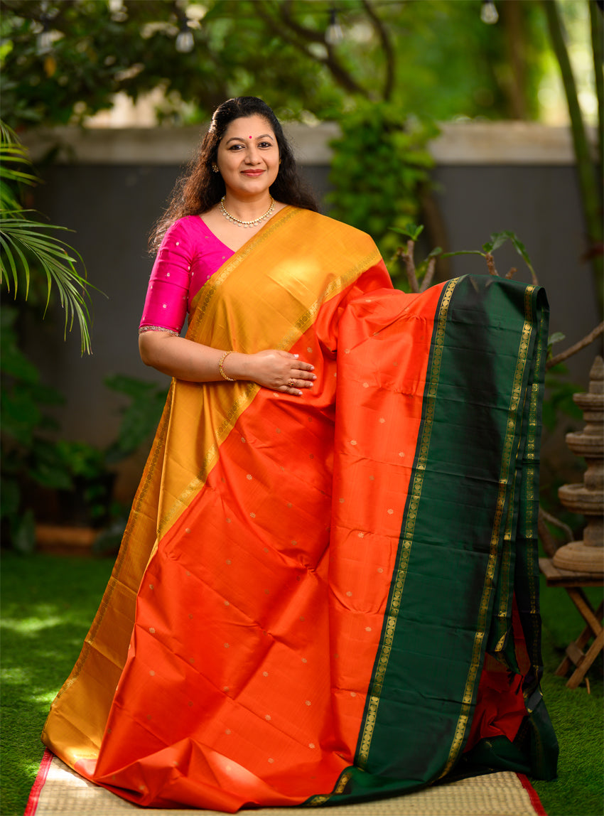 Pure silk, pure zari Ganga Jamuna korvai Kanchivaram in a striking combination of orange on the body, with bottle green and mustard on either side.