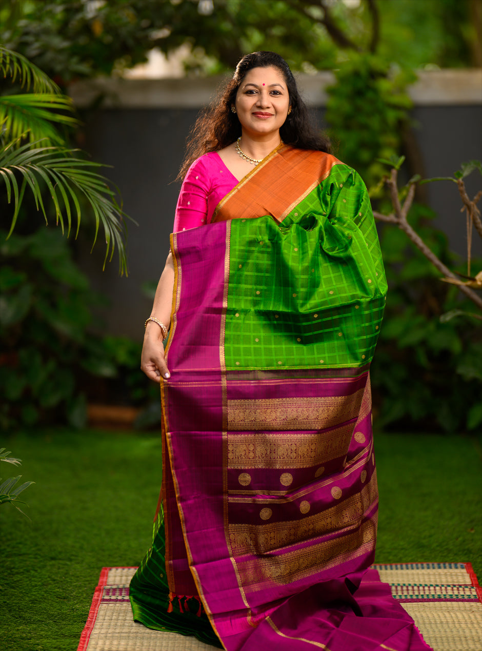 Pure silk, pure zari semi-contrast Ganga Jamuna Kanchivaram featuring a beautiful parrot green kattam on a leaf green body, with delicate floral buttas woven within the checks.