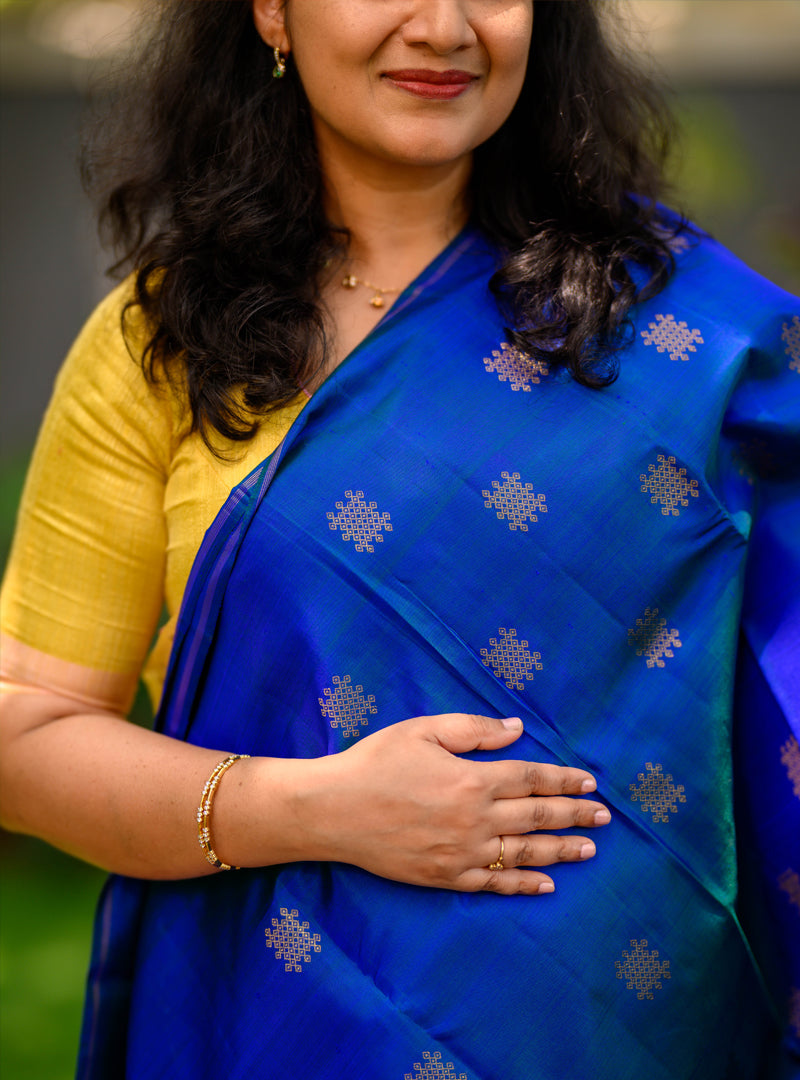 A borderless  kolam butta kanchivaram in shot color peacock blue and rust orange.