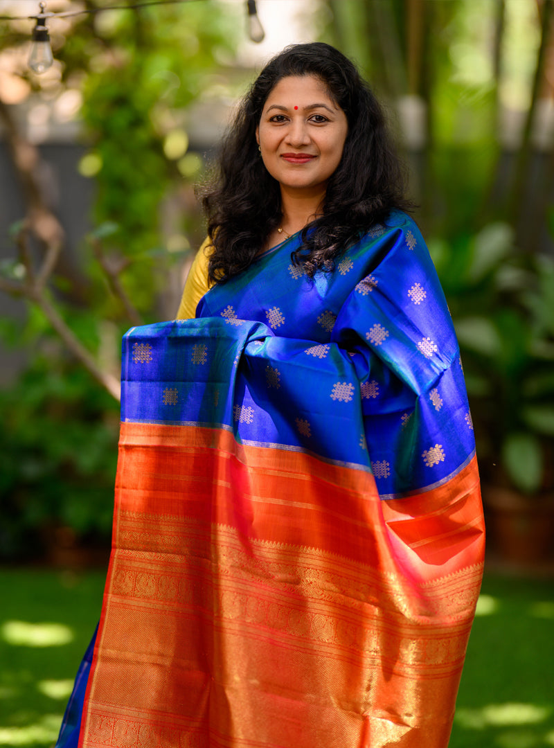 A borderless  kolam butta kanchivaram in shot color peacock blue and rust orange.
