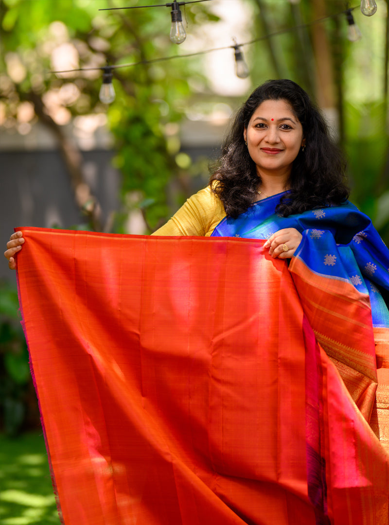 A borderless  kolam butta kanchivaram in shot color peacock blue and rust orange.