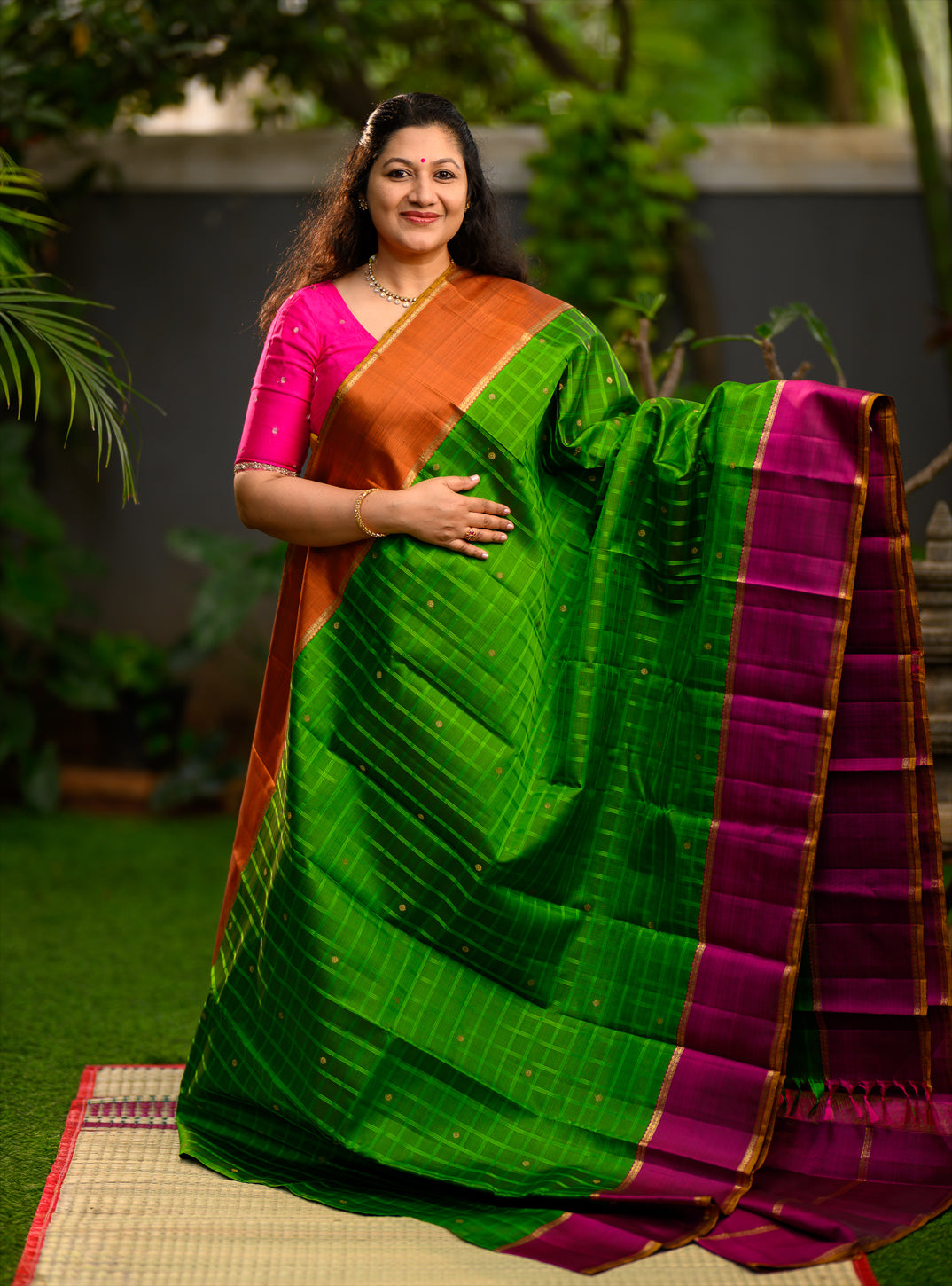 Pure silk, pure zari semi-contrast Ganga Jamuna Kanchivaram featuring a beautiful parrot green kattam on a leaf green body, with delicate floral buttas woven within the checks.