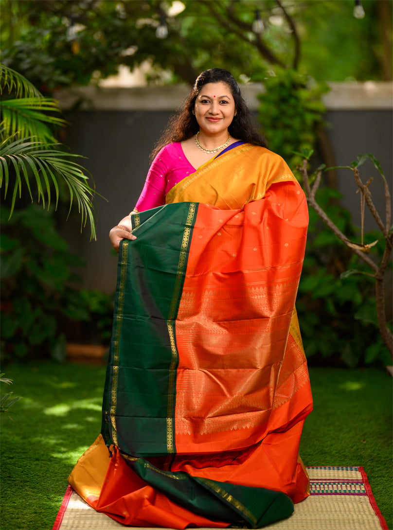 Pure silk, pure zari Ganga Jamuna korvai Kanchivaram in a striking combination of orange on the body, with bottle green and mustard on either side.