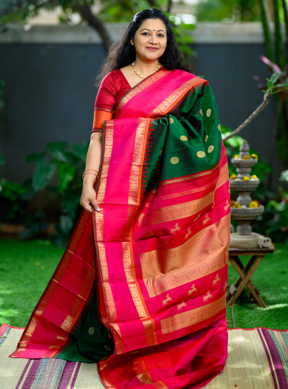 A grand pure silk, pure zari Korvai Kanchivaram in a beautiful bottle green body, contrasted with a vibrant pink border.
