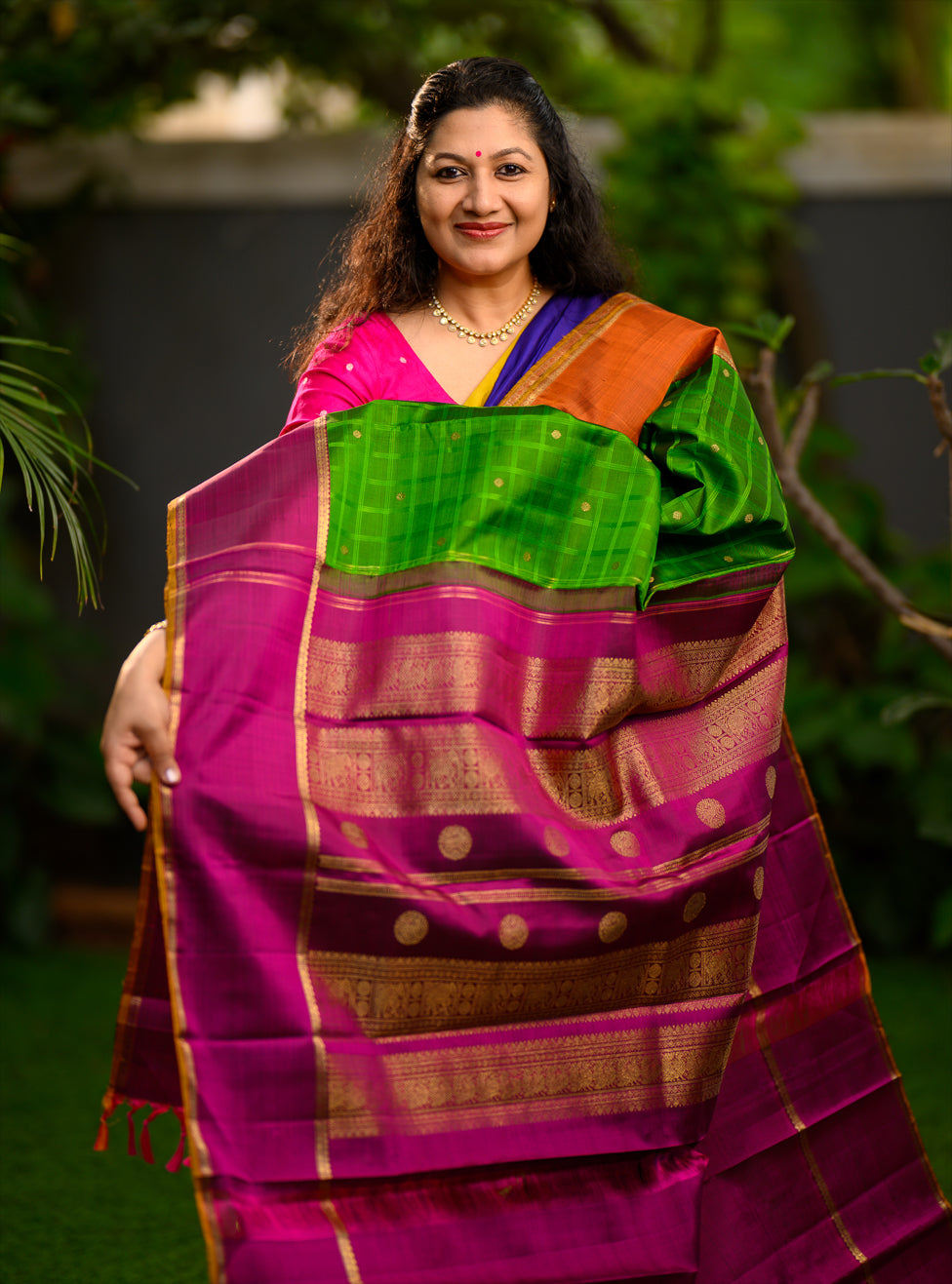 Pure silk, pure zari semi-contrast Ganga Jamuna Kanchivaram featuring a beautiful parrot green kattam on a leaf green body, with delicate floral buttas woven within the checks.