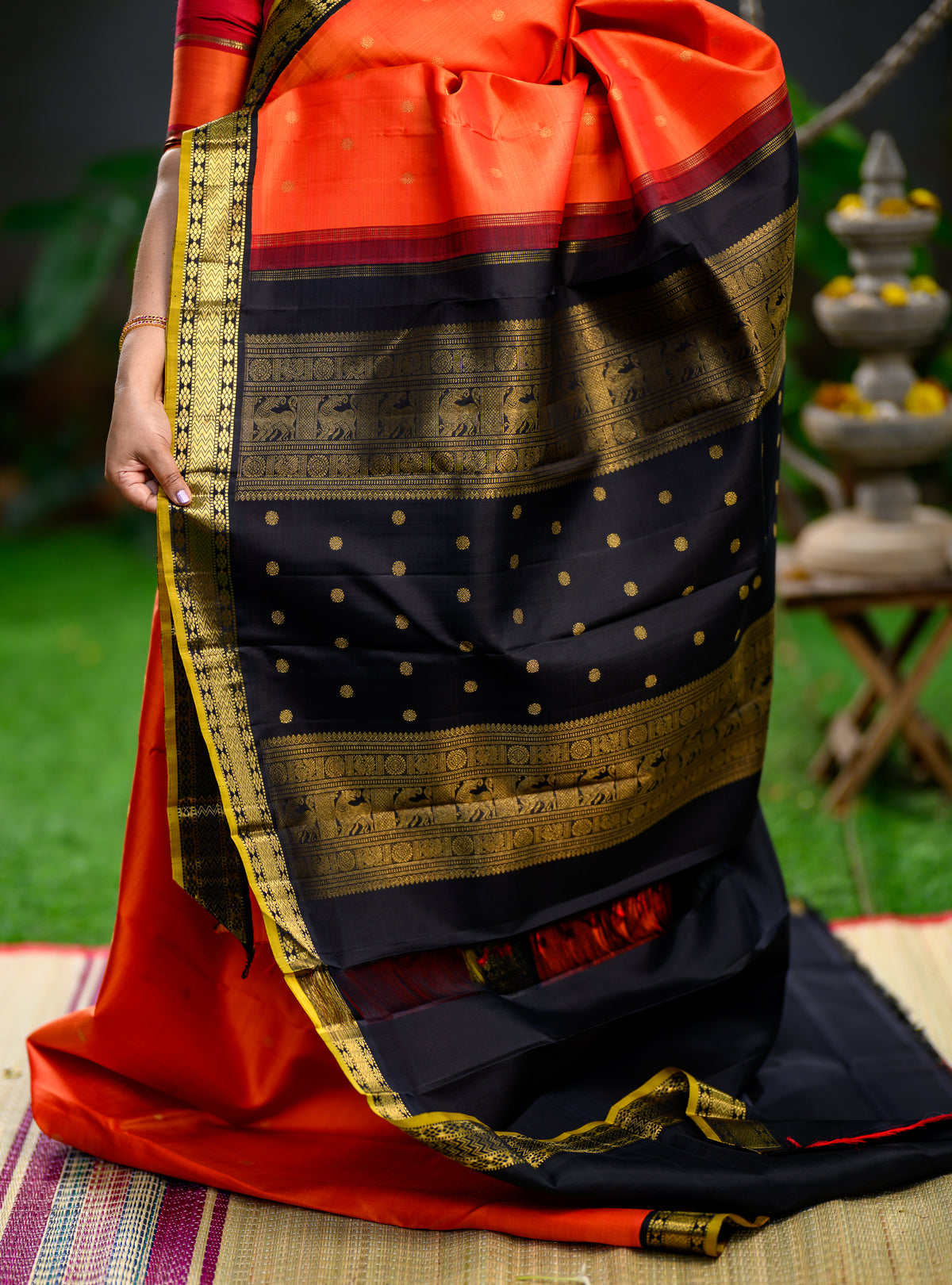 Pure silk, pure zari Korvai Kanchivaram in a bright sun-orange shade, beautifully contrasted with a classic black border.
