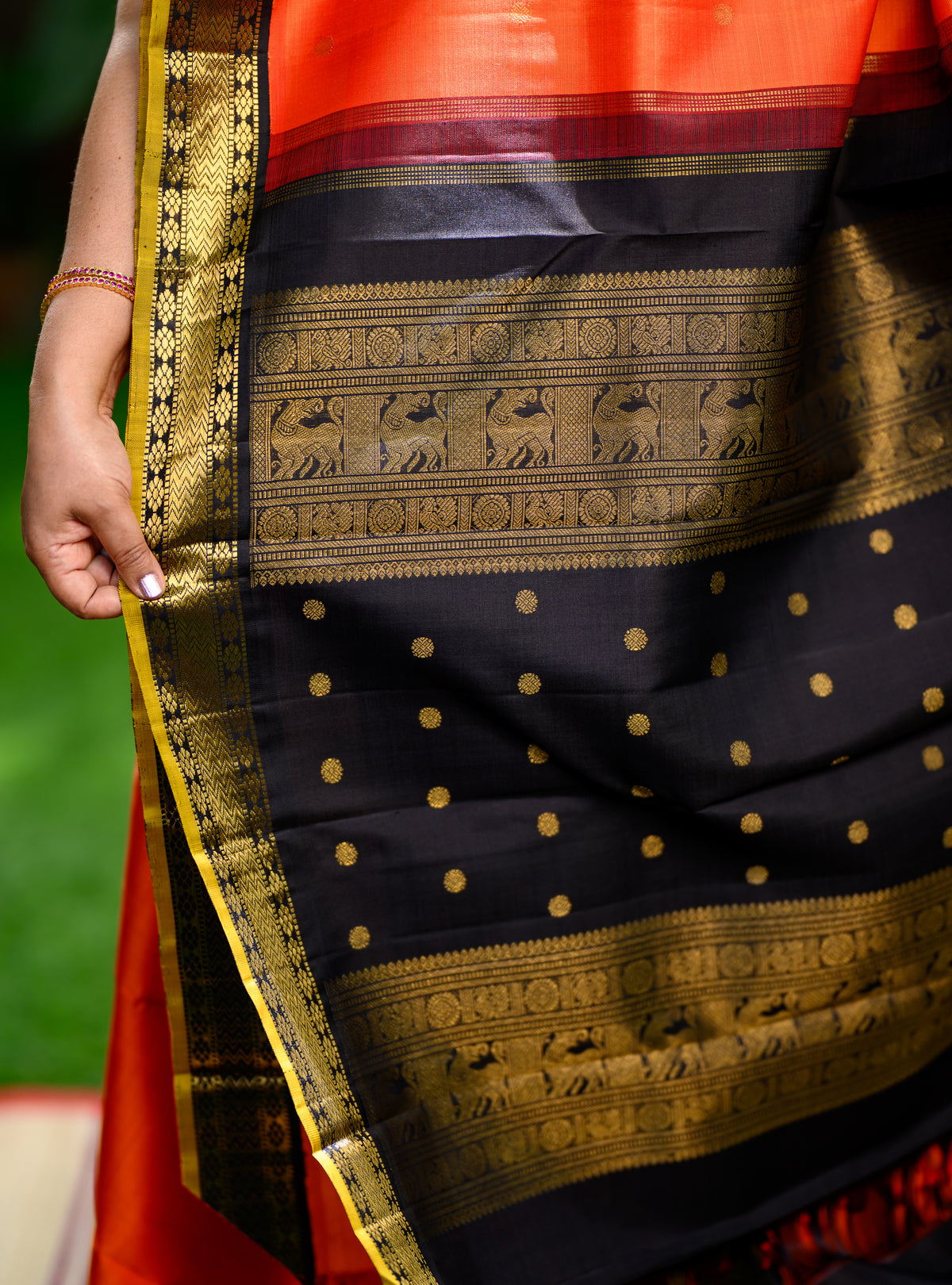 Pure silk, pure zari Korvai Kanchivaram in a bright sun-orange shade, beautifully contrasted with a classic black border.